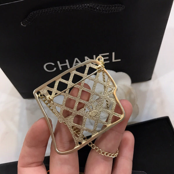 BAG SHAPED BROOCH IN GOLD METAL WITH BLACK CRYSTAL