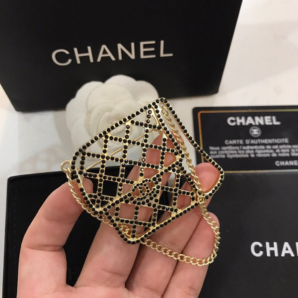 BAG SHAPED BROOCH IN GOLD METAL WITH BLACK CRYSTAL